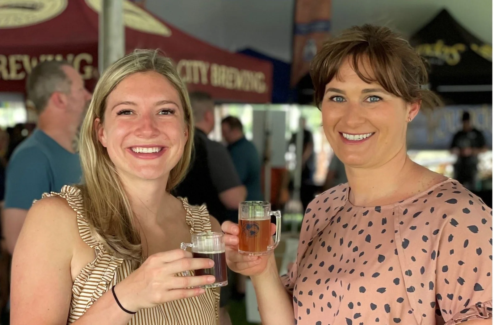 Two smiling World Expo of Beer guests holding tasting mugs